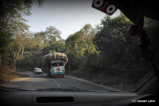 A heavily loaded truck comes straight for our car through the winding roads  at Massanjore, Jharkhand, India by Gautam Lahiri
