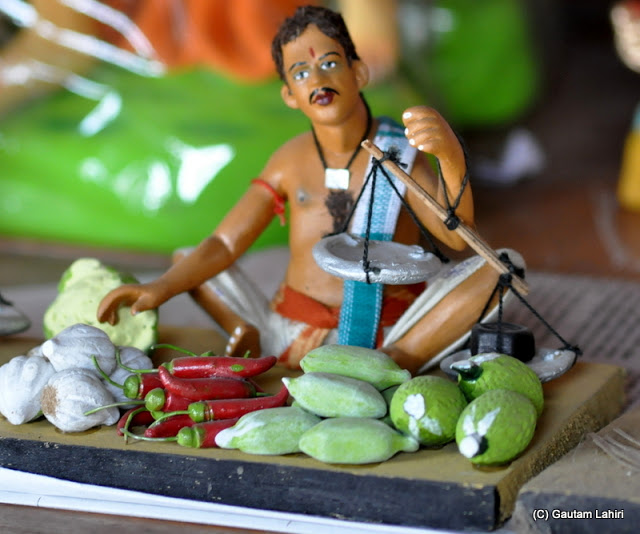 A vegetable seller showing exquisite detailing..even the weight on the left platter pulling down the balance is shown, truly realistic at Krishnanagar, West Bengal, India by Gautam Lahiri