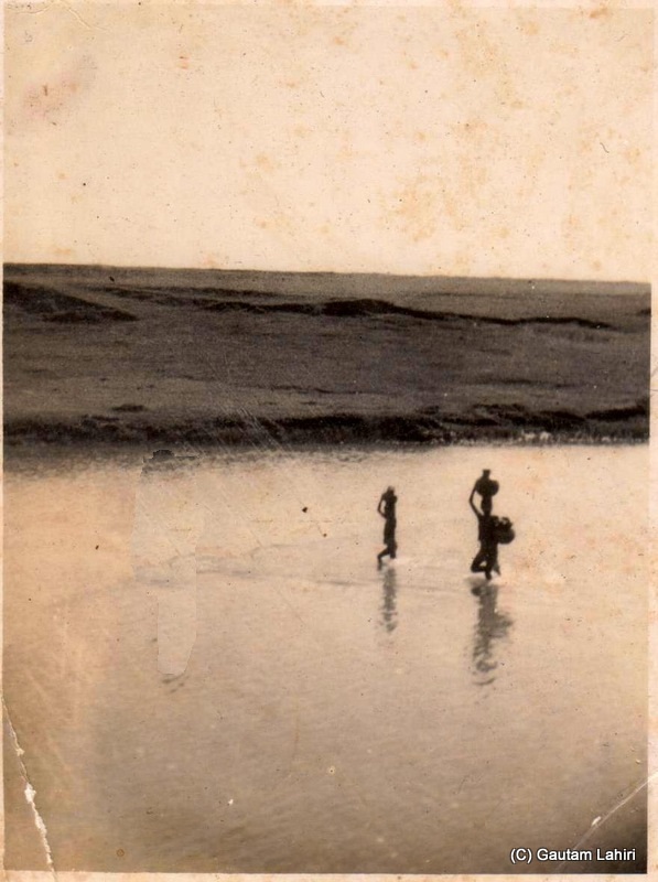 The sand heads furrowed by the sudden torrential river. The local villagers, made bone dry by the fierce sun, never left the chance of extra natural water that came their way. The river looked docile and meek, and within no time inflated as the gush of water started sweeping everything that crossed its path, including a quarter ton Jeep with a trailer at Kishangarh, Rajasthan, India by Gautam Lahiri