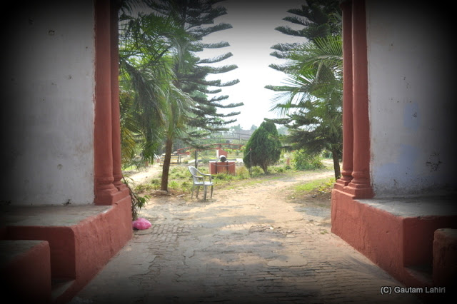 Inside the palace gate, whatever the lens could record the slender road which in all probability reaches the main building. The two sitting areas in red on either side were made for the sentries or soldiers who sat or rested and guarded the palace  at Krishnanagar, West Bengal, India by Gautam Lahiri
