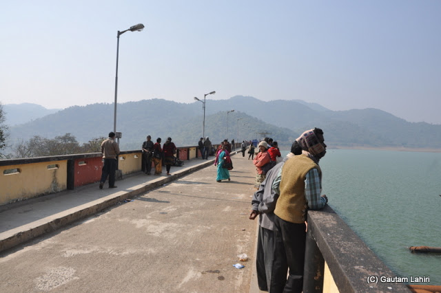 The visitors taste the cool breeze over the dam as we walk past them  at Massanjore, Jharkhand, India by Gautam Lahiri