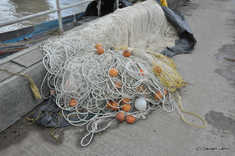 Fishing nets remained coiled up on the harbor floor at Diamond Harbor, West Bengal, India by Gautam Lahiri