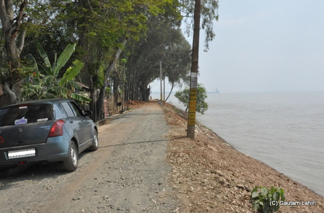 The river bank road hugged the river with a series of tall deciduous trees that continuously hissed in the breeze which came in over the river at Gadiara, Hooghly, West Bengal, India by Gautam Lahiri 