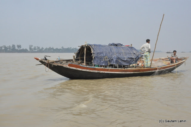 This boat had its net strung across the water and sweeping the depths below in anticipation of fishes getting trapped in the net at Gadiara, Hooghly, West Bengal, India by Gautam Lahiri