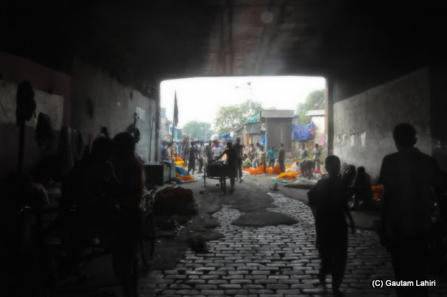 The road made of stone bricks, under the Howrah bridge..looked sinister with its black and white hues with only the flowers like islands of color  at Kolkata, West Bengal, India by Gautam Lahiri