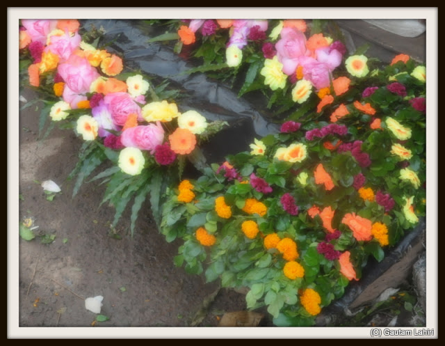Layers of flowers - Marie gold, roses, laced in leaves, sprinkled with water...up for the grabs at Kolkata, West Bengal, India by Gautam Lahiri