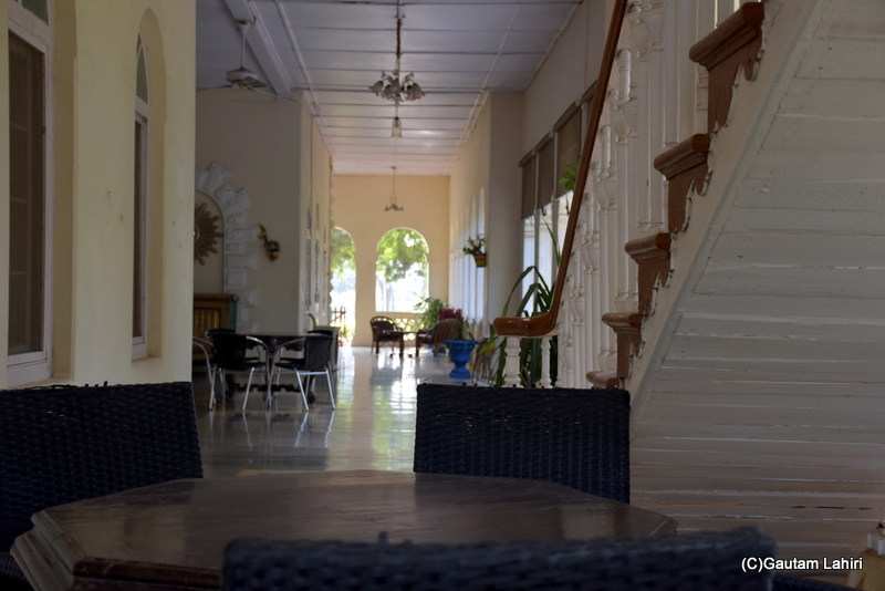 Ornate furniture and staircase balustrade hung below an old chandelier at Orchard Palace by gautam lahiri