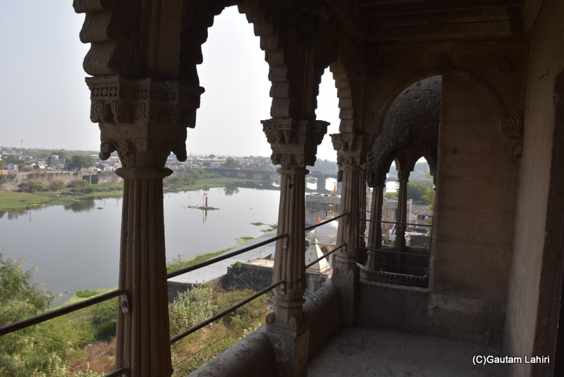The Gondal River, viewed through the ornate balcony's facade, offers a breathtaking scene. The royal family likely spent countless hours observing the sunrise and sunset as they cast their crimson hues over Naulakha Palace in Gondal, Gujarat by gautam lahiri
