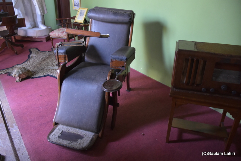 It resembled an 18th-century wooden dental chair with a folding pedestal, neck rest, and foldable arms featuring a tray on the left. This piece served the dental needs of the Royal family within the Naulakha Palace in Gondal by gautam lahiri