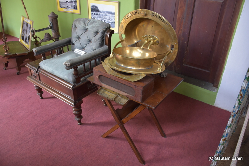 A brass basin with a cover, even the soap holder up front. Two neatly angled brass taps looked down into the basin. A regal chair with drawers made of Mahogony rested. Naulakha Palace, Gondal brings alive the by gone era by gautam lahiri