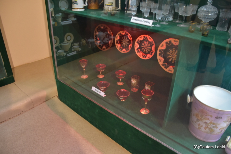 Classic goblets, cut glass and porcelain plates with plated gold shone a red wine color through he delicate showcases at Naulakha Palace, Gondal by gautam lahiri